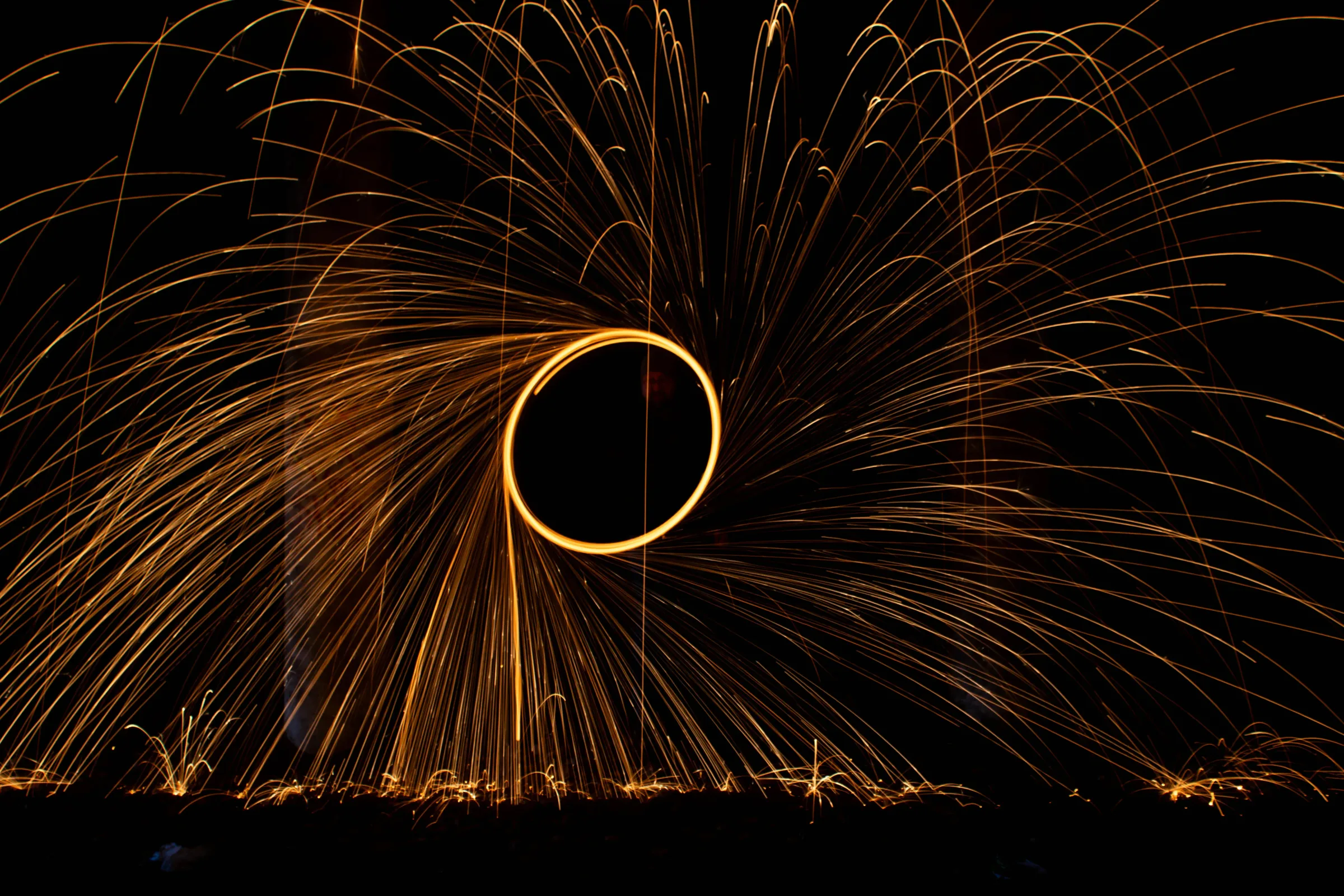Steel wool spinning long exposure, a circle of golden sparks against a dark night sky